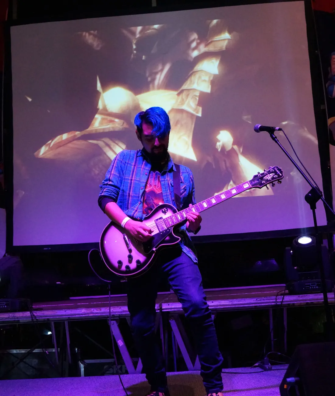 Kris Escobar on stage with a Les Paul, blue hair, pink stage light